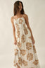 Woman wearing a white dress with brown floral patterns against a plain background