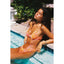Woman in a colorful bikini sitting by a pool with greenery in the background