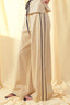 Beige pants with a black stripe worn by a person against a yellow curtain background