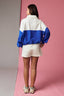 Person wearing a blue and white jacket and shorts on a pink and gray gradient background