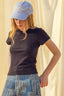 Woman wearing a blue cap and dark sweater with a light background