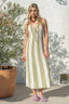 Woman wearing a green and white striped dress standing outdoors next to a potted plant.