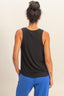 Person wearing a black sleeveless top and blue pants on a beige background