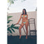 Woman in a blue bikini holding a hose against a white wall with green leaves.