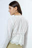 Woman wearing a white lace top with a plain background