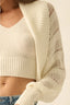 Beige knit cardigan worn over a beige top on a plain background