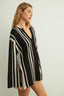 Woman wearing a black and white striped dress against a plain background