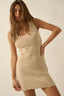 Woman wearing a beige crochet dress against a plain background