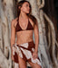 Woman wearing a brown bikini with a matching sarong against a tree bark background