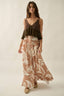 Woman wearing a brown top and patterned pants on a plain background