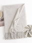 Light gray scarf with fringe on a white surface