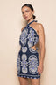 Woman wearing a blue and white patterned dress on a beige background