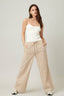 Woman wearing a white top and beige striped pants on a plain background