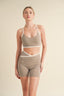 Woman wearing a beige sports bra and shorts set on a beige background
