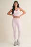 Woman wearing a pink athletic outfit with a cap on a beige background