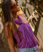 Woman wearing a purple top with a pattern, standing outdoors with a blurred natural background