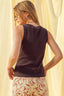 Woman wearing a sleeveless top and floral skirt against a light curtain background
