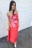 Woman in a pink dress standing in front of a graffiti-covered wall.