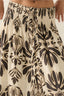 Beige pants with black floral pattern and button details.