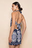 Woman wearing a blue and white patterned dress on a beige background