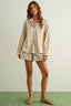 Woman wearing a beige striped shirt and shorts set on a plain background