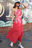 Woman in a pink dress standing in front of a graffiti-covered wall.