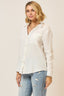 Woman wearing a white blouse and blue jeans against a plain background