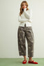 Woman wearing a white long-sleeve top and gray pants with bow patterns on a light background