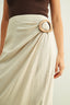 Beige skirt with a wooden belt buckle worn by a person on a light background