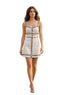 A woman walks down a gravel path in a garden wearing a cream-colored sleeveless mini dress with black trim and a central decorative detail.