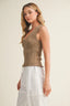 Woman wearing a brown knitted top and white pants on a beige background