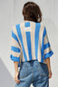 Person wearing a blue and beige striped sweater against a gray background
