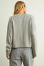 Person wearing a gray sweater and plaid pants against a plain background
