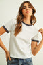 Woman wearing a white t-shirt with black trim and blue jeans on a plain background