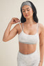 Woman wearing a light gray sports bra and leggings against a beige background