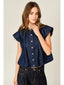 Woman wearing a denim top with ruffled sleeves on a plain background