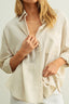 Woman wearing a beige linen shirt against a plain background