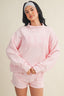 Person wearing a pink sweatshirt and shorts set on a beige background