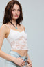 Woman wearing a white lace top and light blue jeans against a gray background