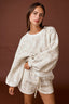 Woman wearing a white fleece outfit against a brown background