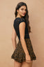 Woman wearing a black lace top and leopard print skirt on a beige background