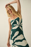 Woman wearing a green and white floral dress against a plain background