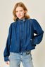 Woman wearing a blue denim jacket and jeans on a beige background