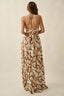 Woman wearing a long, patterned dress with a neutral background