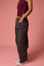 Person wearing a purple top and dark pants on a pink background