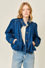 Woman wearing a blue denim jacket and jeans on a plain background