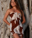 Woman wearing a brown strapless dress with floral patterns against a textured wall.