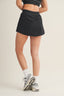 Person wearing a black skirt with white socks and sneakers on a beige background