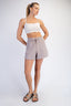 Woman wearing a white sports bra and gray shorts on a white background