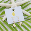 Starfish-shaped earrings on a 'lotus & luna' branded card with green leaves and white starfish in the background.